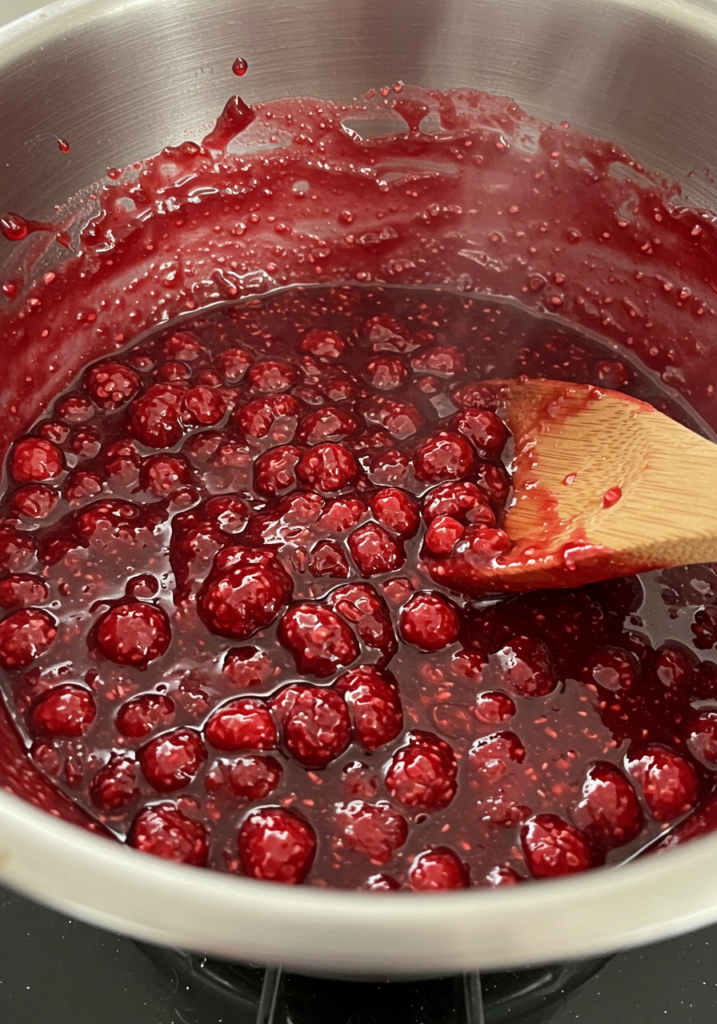 Homemade raspberry filling being mixed in a bowl.